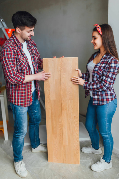 Happy couple choosing laminate flooring for new apartment  - Фото, изображение
