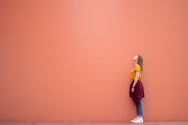 young stylish girl stands on the coral wall and looks up - Photo, Image