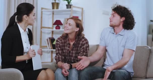 Woman house agent make a deal with a young couple after they discuss the term of a house rent at the end they shaking hands - Video, Çekim