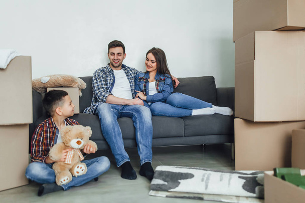 boy with teddy bear sitting on floor with mother and father in new home - Foto, immagini