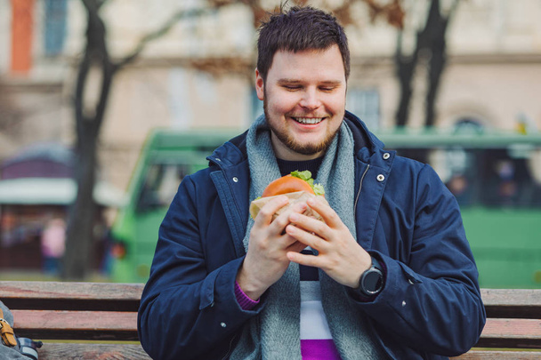 young adult man eating hamburger - Zdjęcie, obraz