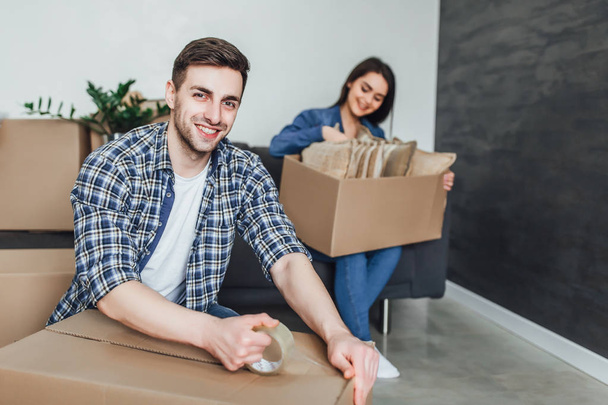 Happy young couple packing cardboard boxes during relocation - Photo, Image