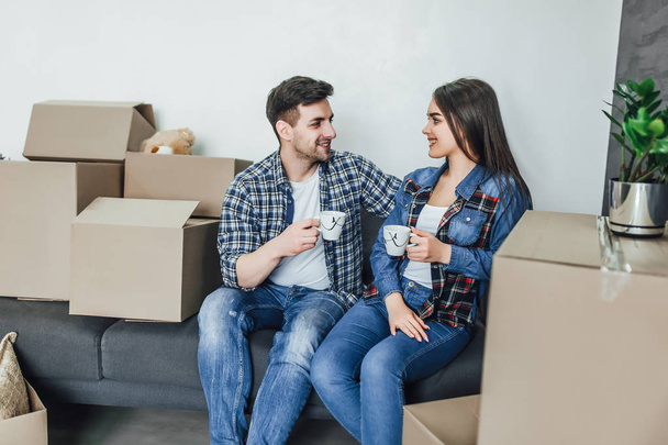 Couple relaxing on sofa with hot drinks in new home - Fotografie, Obrázek