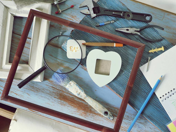 Tools, frame, notebook, congratulation on a wooden table, top view, father's day - Zdjęcie, obraz