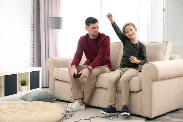 Батько і син грають у відеоігри вдома
 - Фото, зображення