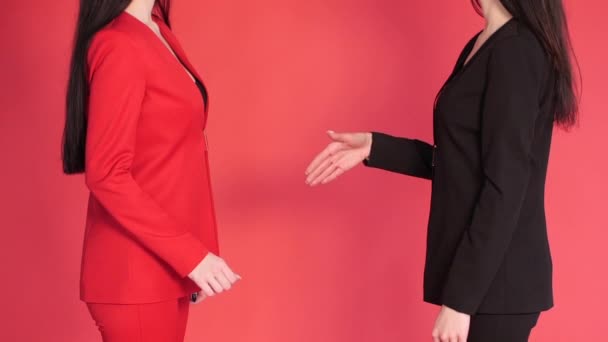Twee zakenpartners schudden de handen in de rode achtergrond. - Video