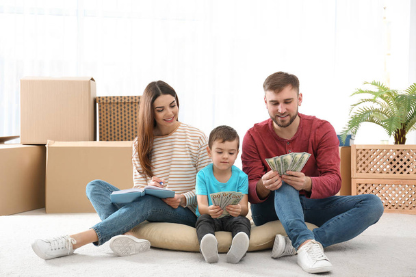 Счастливая семья с деньгами на полу дома
 - Фото, изображение