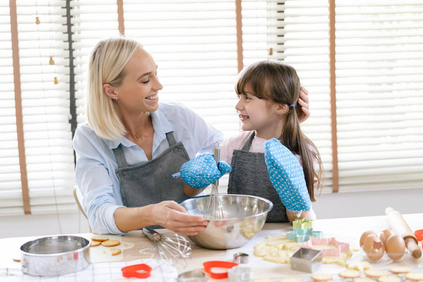 Симпатична маленька дівчинка і її мати готують тісто в наборі
 - Фото, зображення