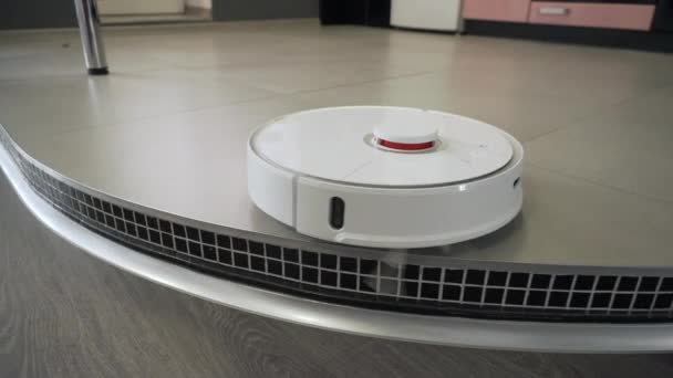 La aspiradora robótica limpia el suelo de la cocina. Tecnología inteligente en un hogar moderno
. - Imágenes, Vídeo