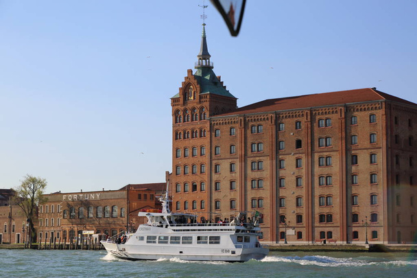 VENICE, ITALY - APRIL 19, 2019: View from the waterbus (vaporetto, canal boat, steamboat, motorboat used for public transportation) on the sights of the city Venice, nature, citizens and tourists. - Фото, изображение