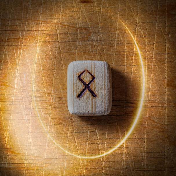 Othala. Handmade scandinavian wooden runes on a wooden vintage background in a circle of light. Concept of fortune telling and prediction of the future - Photo, Image