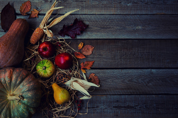 秋の葉、赤リンゴ、トウモロコシとカボチャの秋の背景。コピースペースで熟成木材の秋の収穫。季節のオファーや休日のポストカード、トップビューのためのモックアップ。トーン画像. - 写真・画像