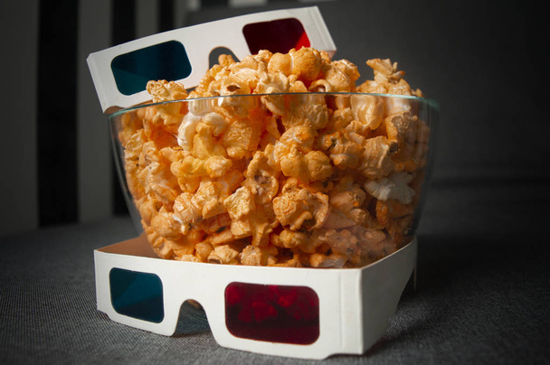 okulary 3D i cheesy popcorn leżą w szklanej płycie na szarym łóżku - Zdjęcie, obraz