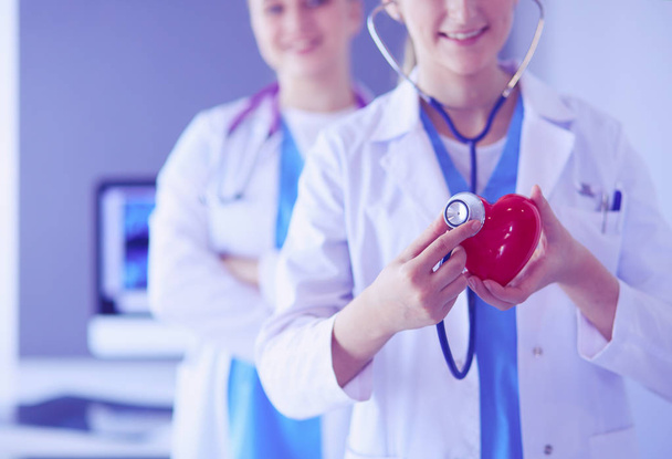 Cropped shoot of two young doctors female with stethoscope holding heart. - Fotoğraf, Görsel