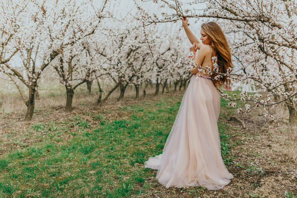 Młoda piękna kobieta pozuje obok kwitnących drzew - Zdjęcie, obraz