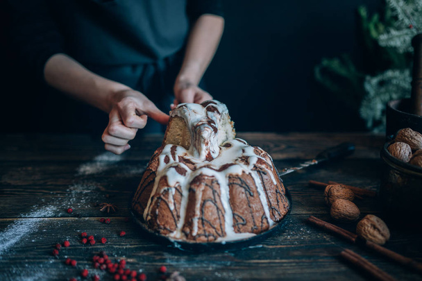 Cooking homemade cake Christmas Eve at home rustic kitchen. Woman's hands make pudding. Ingredients for cooking christmas baking on dark wooden table. Merry Christmas and Happy Holidays! Toned image. - 写真・画像