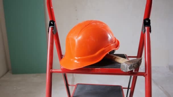 Close-up slow motion video van werktuigen en rode helm liggend op metalen trapje in gebouw in aanbouw of renovatie - Video