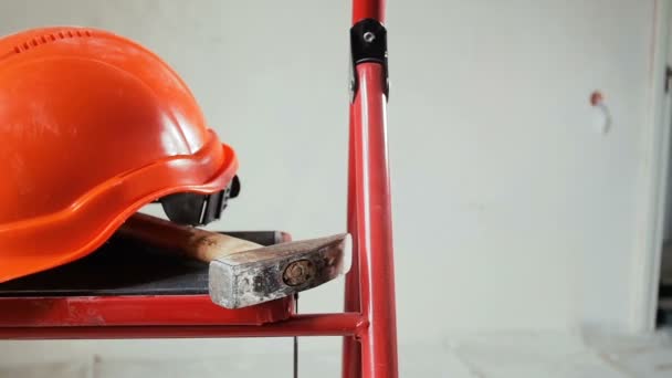 Closeup vídeo em câmera lenta de ferramentas de trabalho e capacete vermelho deitado na escada rolante de metal no edifício em construção ou renovação
 - Filmagem, Vídeo