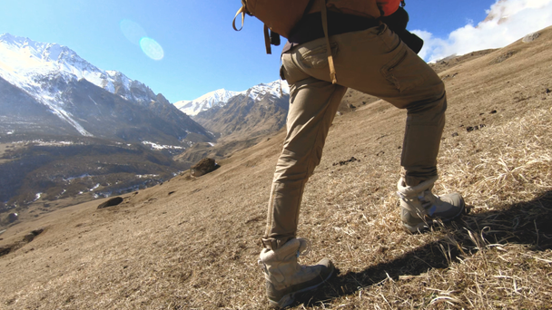 Pernas de uma menina viajante subir em um fundo de picos cobertos de neve em um dia ensolarado
 - Filmagem, Vídeo