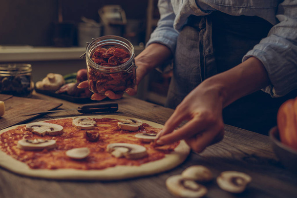 Cook hands. Close up on hands, some ingredients around on table. Fresh original Italian raw pizza, preparation in traditional style. Ingredients and spices for making homemade pizza on wooden table. - Φωτογραφία, εικόνα