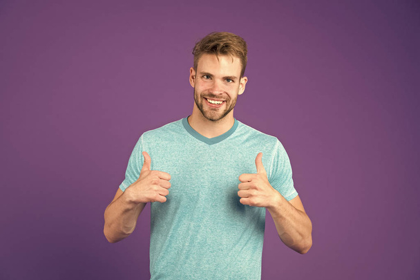 Approve or recommend concept. Man with brilliant smile unshaven face shows thumbs up gesture violet background. Man happy cheerful face support or recommend. Guy happy emotional approve expression - Fotó, kép