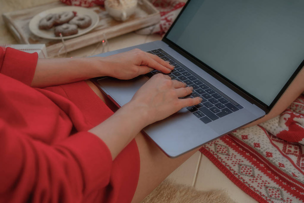 Christmas online shopping. Woman buys presents, prepare to xmas eve. Female with laptop, copy space on screen. Hot coffee, spice and almond cakes on tray. Cozy blanket. Toned image. Soft focus. - Foto, afbeelding