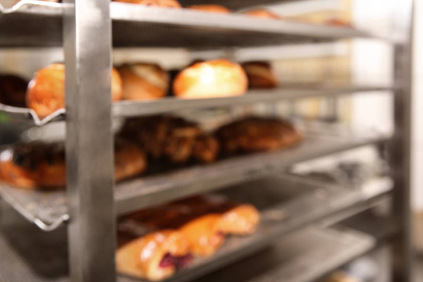 Vista borrosa del estante con pasteles en el taller de panadería
 - Foto, Imagen