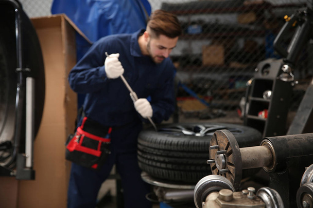 Technicien travaillant avec roue de voiture à l'atelier de réparation automobile
 - Photo, image