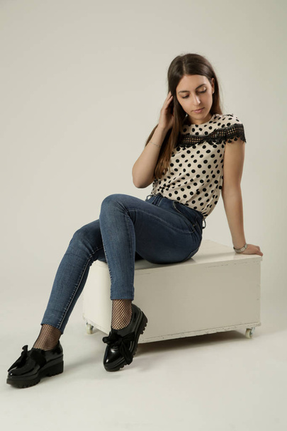 Full-length portrait of a beautiful young woman in the studio wearing polka dots blouse and jeans - Fotoğraf, Görsel