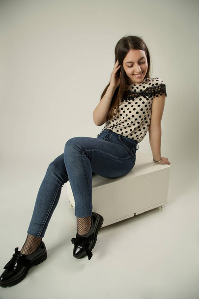 Повнометражний портрет красивої молодої жінки в студії в полькових крапках блузка і джинси
 - Фото, зображення