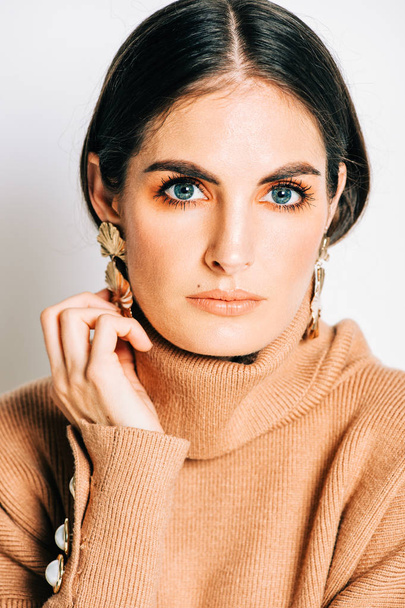 Studio shot of beautiful young woman with dark hair and blue eyes, , wearing brown makeup and turtle neck pullover - Photo, Image