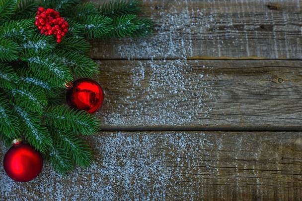 Weihnachtlicher Hintergrund für Grußkarte mit Tannenzweigen, Dekoration und roten Kugeln, auf dunklem Holzbrett. Ansicht von oben mit Kopierraum für Text. - Foto, Bild