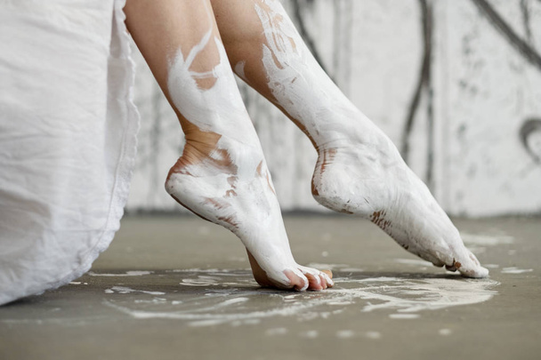 Nuoren taiteellisesti abstraktin maalatun naisen jalat ja jalat, ballerina valkoisella maalilla
 - Valokuva, kuva