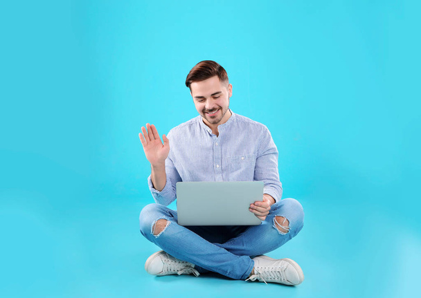 Man using laptop for video chat on color background - Foto, afbeelding