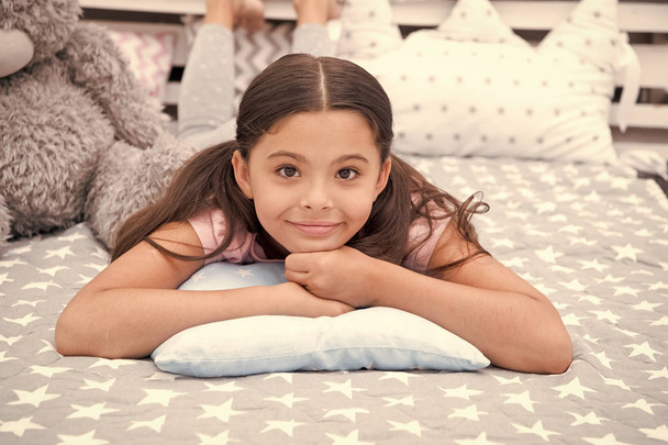Just relaxing. Girl child lay on pillow in her bedroom. Kid prepare to go to bed. Pleasant time stylish interior. Girl kid long hair cute pajamas relaxing on pillow in bedroom. Time to sleep or nap - Zdjęcie, obraz