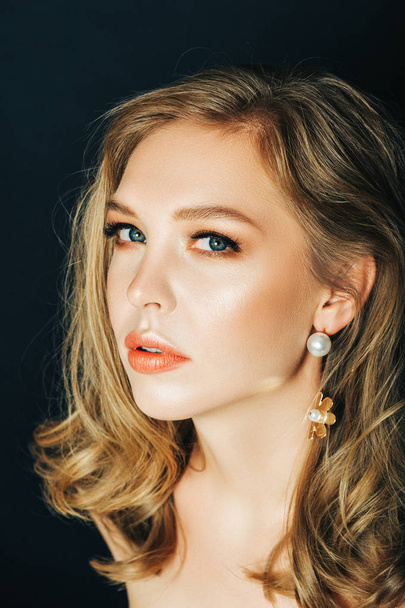 Close-up portret van mooie jonge vrouw met blond haar en professionele make-up, poseren op zwarte achtergrond - Foto, afbeelding