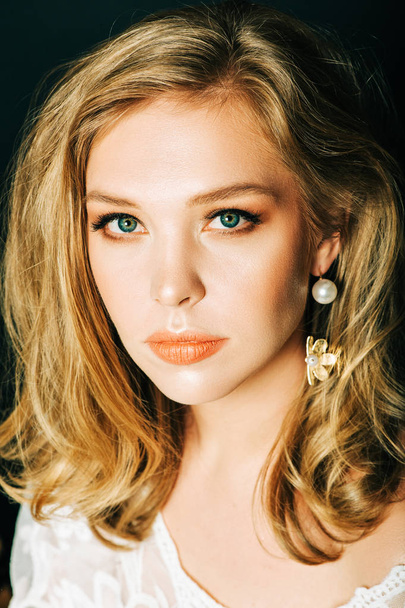 Close up retrato de bela jovem com cabelo loiro e profissional compõem, posando sobre fundo preto
 - Foto, Imagem