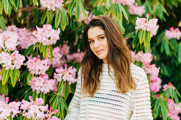 Внешний портрет красивой молодой женщины белый вязаный пуловер, позирующий в весеннем саду
 - Фото, изображение
