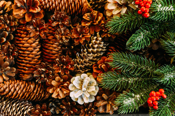 Christmas background with fir tree, red berries and fir cones. View with copy space. - Фото, изображение