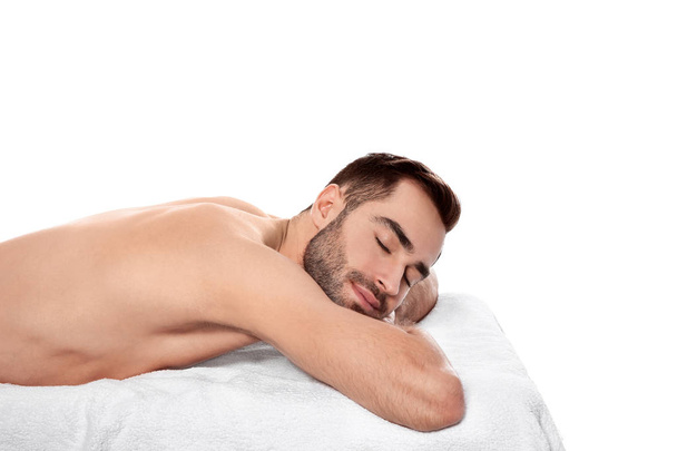 Handsome man relaxing on massage table against white background. Spa service - Photo, Image