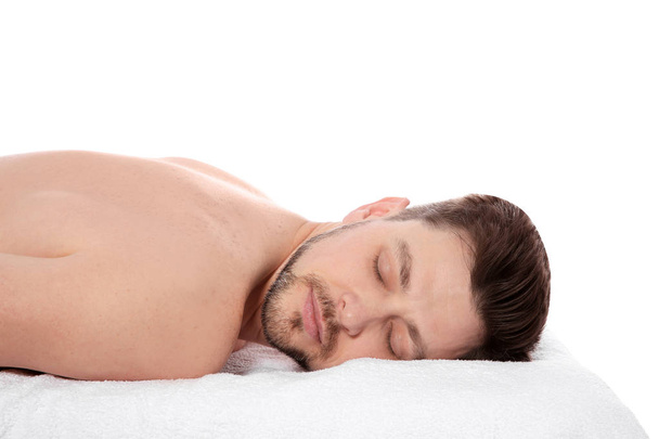 Handsome man relaxing on massage table against white background. Spa service - Photo, image