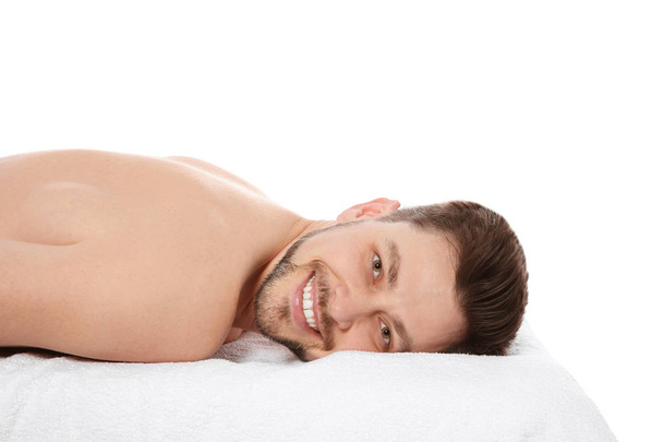 Handsome man relaxing on massage table against white background. Spa service - Photo, image