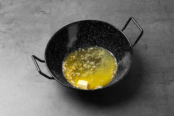 Frying pan with melting butter on grey table - Photo, Image