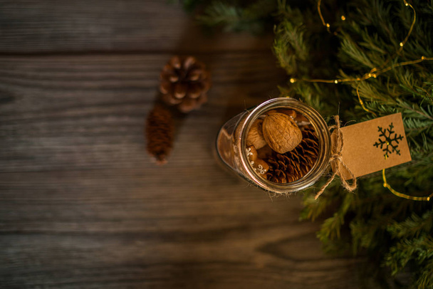 Christmas gift with homemade gingerbread cookies, nuts and chocolates. Glass jar, fir branches, Christmas spices and decor. Winter holidays, New Year or Christmas concept. Top view with copy space. - Foto, Imagem