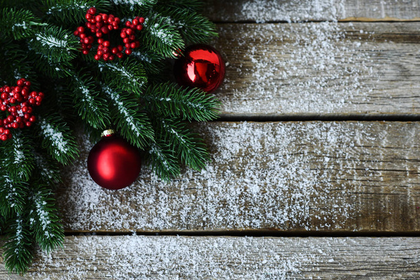 Sfondo natalizio per biglietto di auguri con rami di albero di Natale, decorazione e palline rosse, su tavola di legno. Vista dall'alto con spazio di copia per il testo
. - Foto, immagini