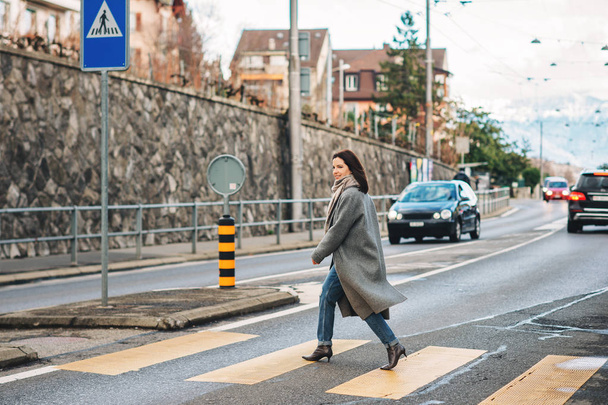 Відкритий портрет прекрасної жінки носять Сіре пальто, перетинаючи дорогу. Зображення взято в місті, Швейцарія - Фото, зображення