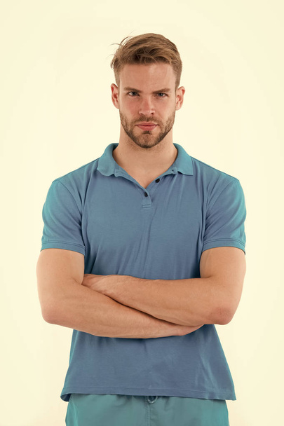 Man with trendy hairstyle and small bristle isolated on white background. Sportsman in blue outfit on training, health and fitness concept. Athlete with sexy muscular body folding arms at his chest - Zdjęcie, obraz