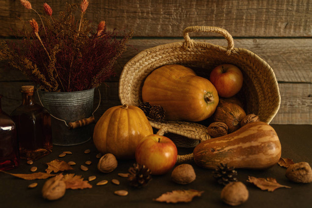 Colored fall vegenables on the vintage boards. Autumn decorations in wicker basket. A cornucopia with squash, gourds, pumpkins, cones, wheat and leaves. Toned image with copy space. Harvest time. - Foto, Imagen