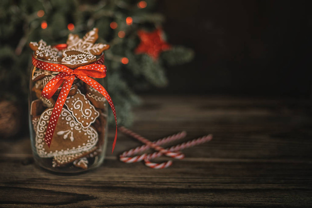 Christmas gift with homemade gingerbread cookies, nuts and chocolates. Glass jar, fir branches, Christmas spices and decor. Winter holidays, New Year or Christmas concept. Toned image. Soft focus. - Фото, зображення