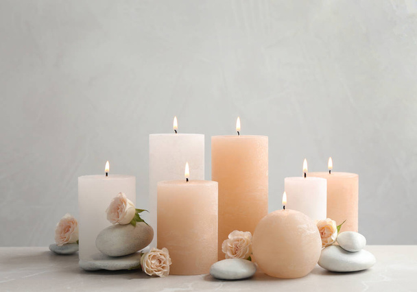 Beautiful composition with candles on table against grey background - Foto, Imagem